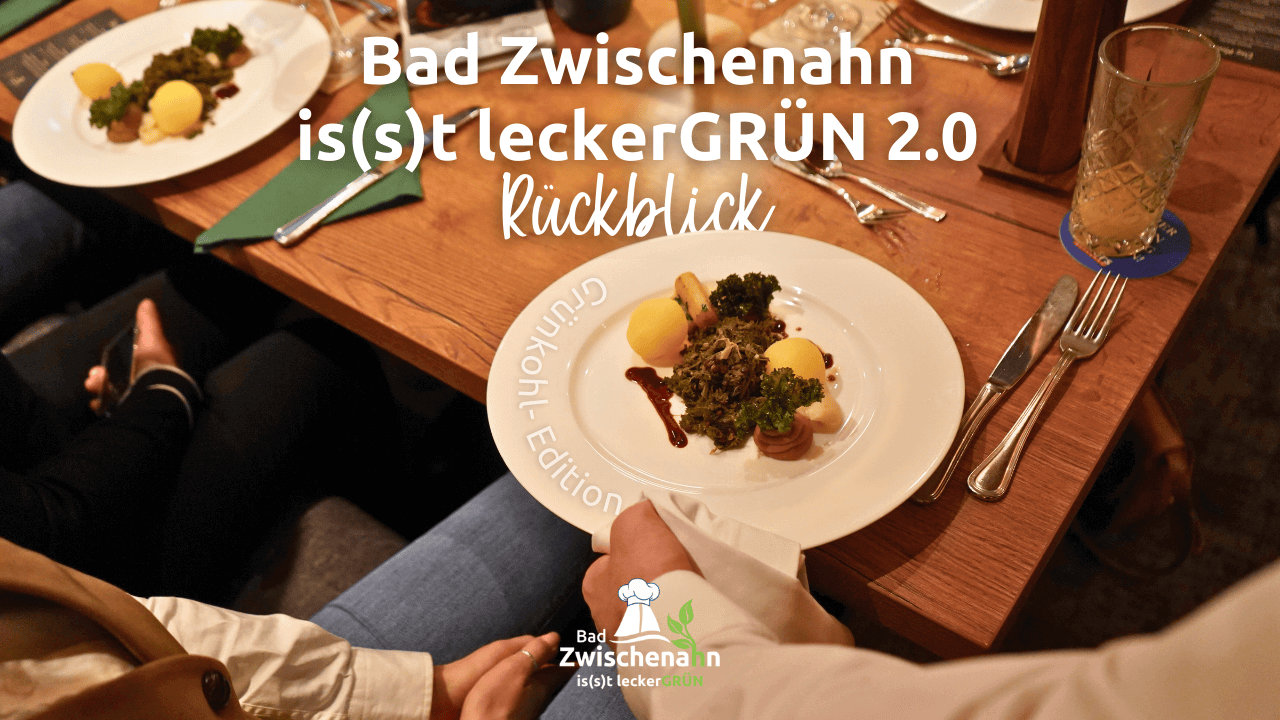 Tisch mit zwei Tellern, auf denen jeweils ein Gericht mit Grünkohl und Kartoffeln angerichtet ist, darüber weißer Text 'Bad Zwischenahn is(s)t leckerGRÜN 2.0 Rückblick'.