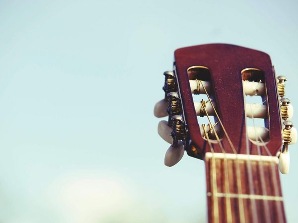 Nahaufnahme des Kopfes einer klassischen Gitarre mit Stimmmechaniken vor hellem Himmel.