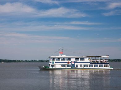 Ein Schiff der Weissen Flotte fährt bei Sonnenschein vollbesetzt über das Zwischenahner Meer.