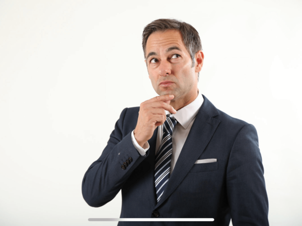 Thiess Neubert im dunklen Anzug mit gestreifter Krawatte, der nachdenklich zur Seite schaut und sich das Kinn hält