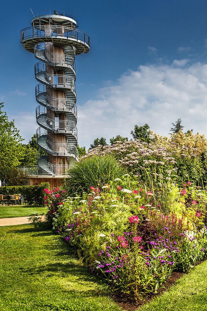 Imposantes Blumenbad und grüne Wiesen vor dem Aussichtsturm im Park der Gärten.