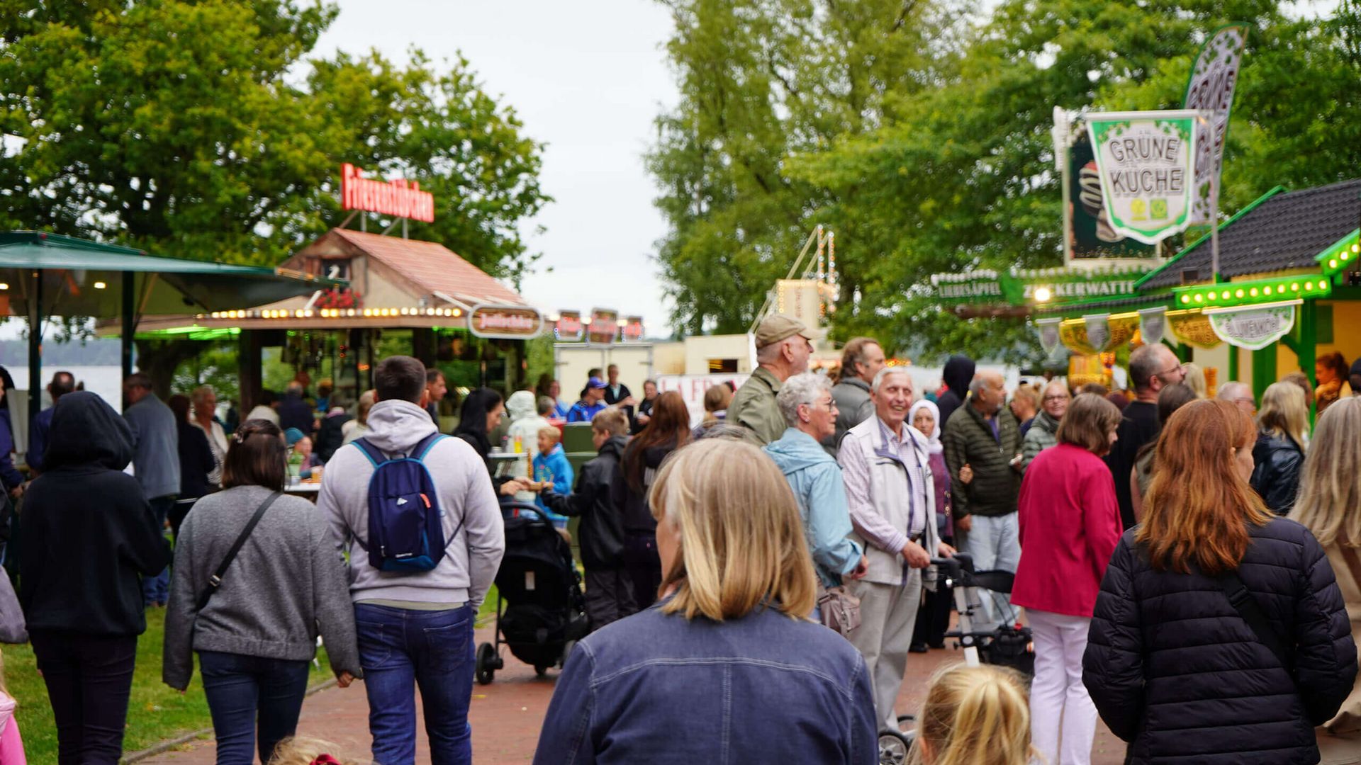 Menschenmenge auf einem Weg im Kurpark mit Ständen und Bäumen im Hintergrund.