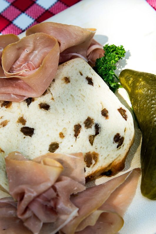 Traditioneller Ammerländer Schinken auf Rosinen-Stutenbrot, serviert auf rustikalem Holzteller mit Salat.